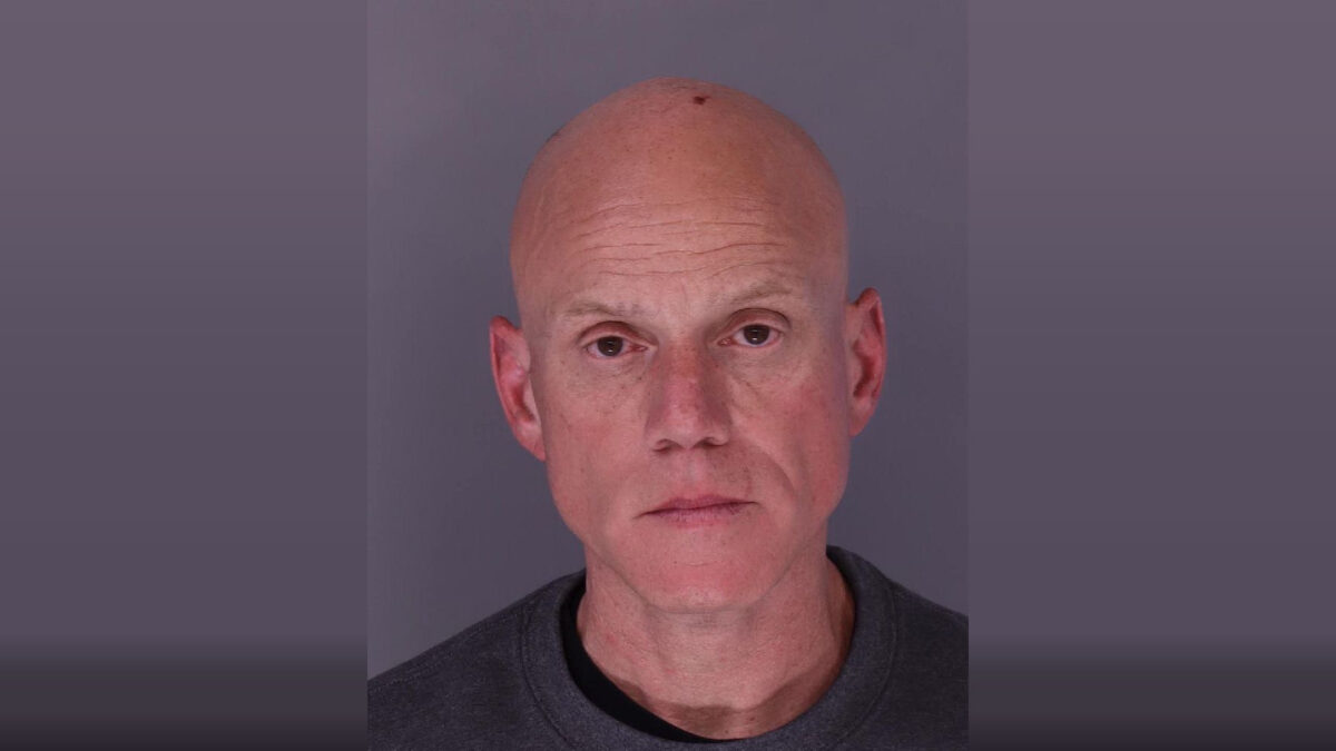 Head-and-shoulders portrait of a bald man against a plain gray background.