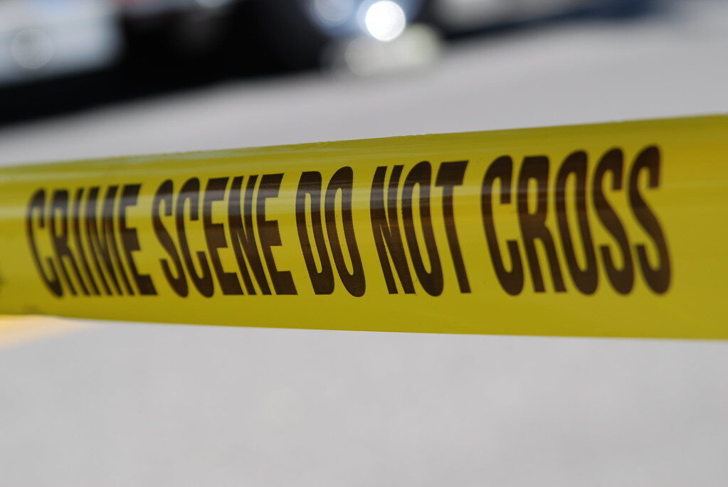 Yellow crime scene tape with bold black warning text stretched across a blurred background.