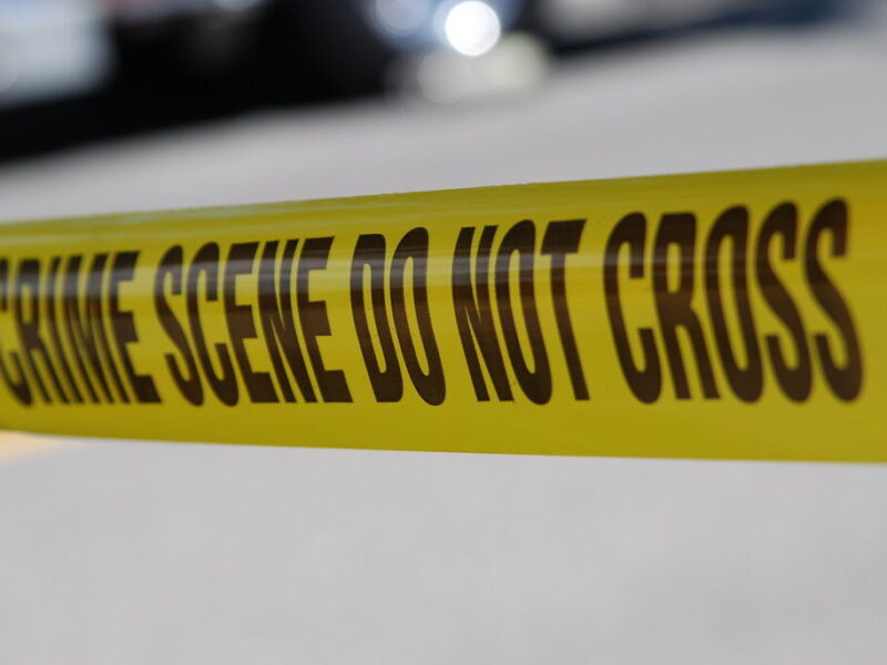 Yellow crime scene tape with bold black warning text stretched across a blurred background.
