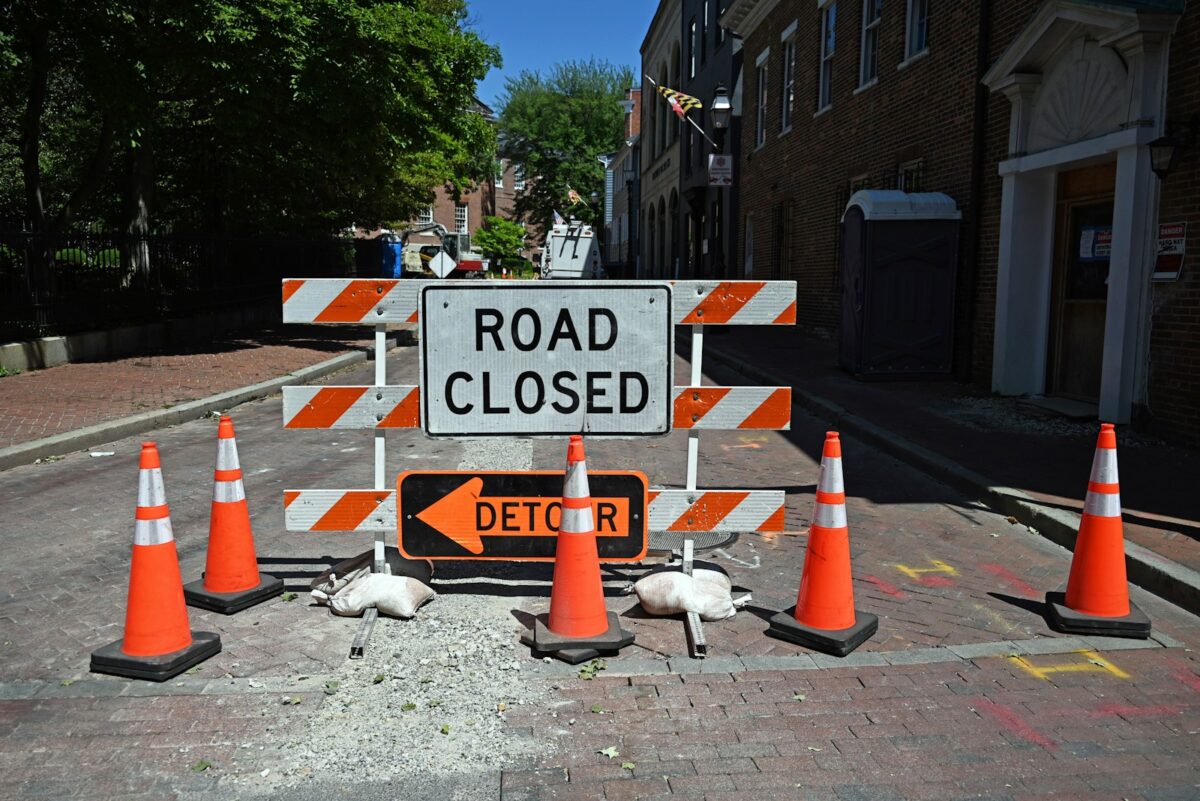 A road closed sign surrounded by orange traffic cones