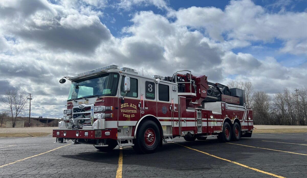 Red fire truck parked in an empty lot under a cloudy sky.
