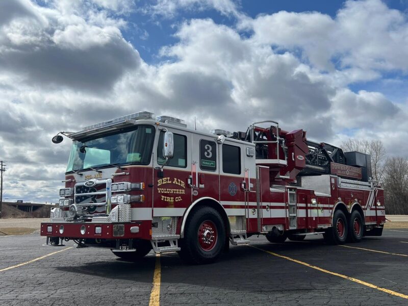 Red fire truck parked in an empty lot under a cloudy sky.