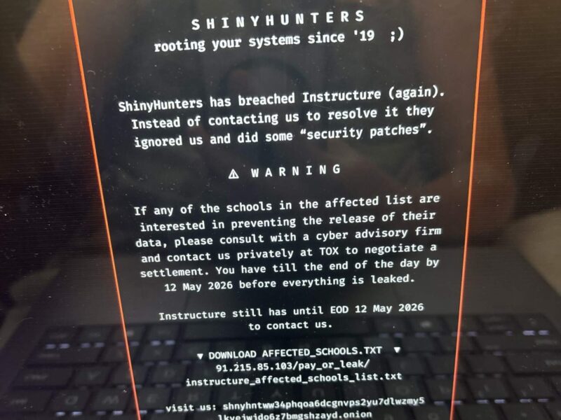 Laptop screen showing a black warning page from ShinyHunters about a security breach and leaked school data.