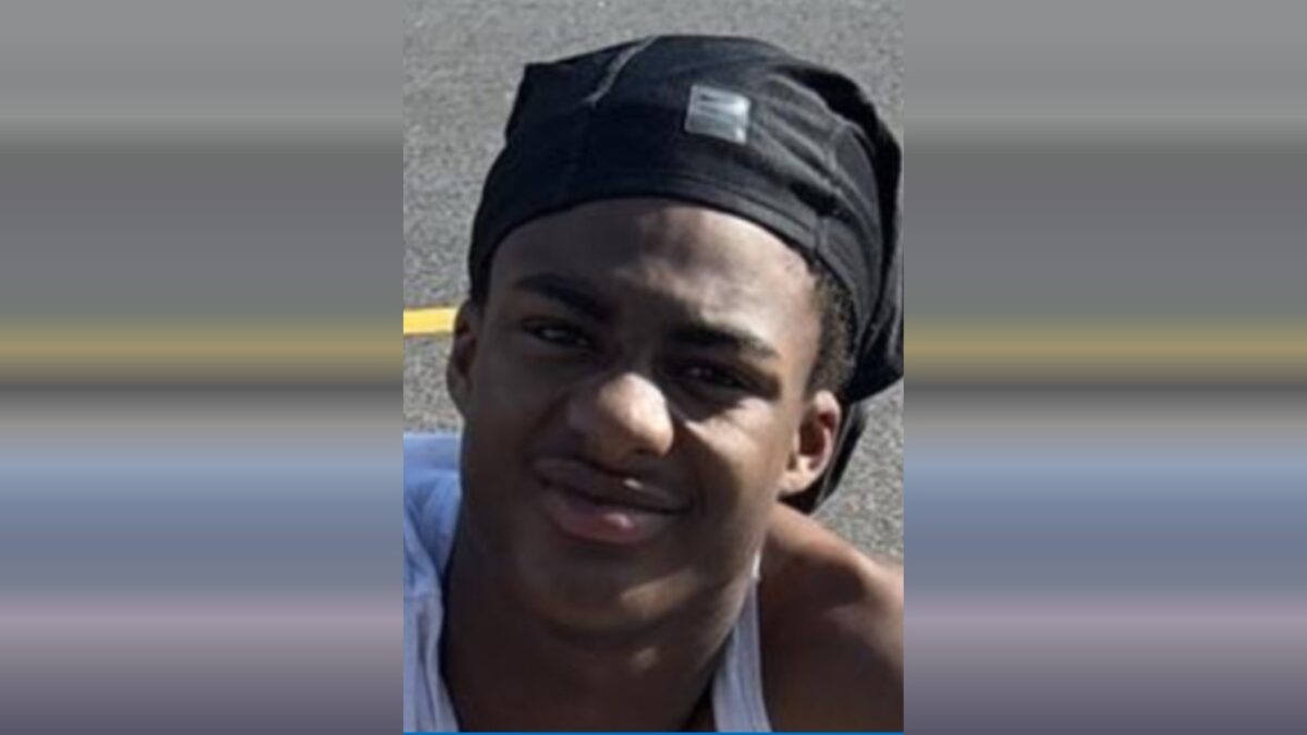Portrait of a young man wearing a black headwrap and white tank top outdoors.
