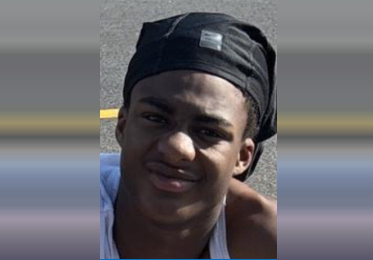 Portrait of a young man wearing a black headwrap and white tank top outdoors.