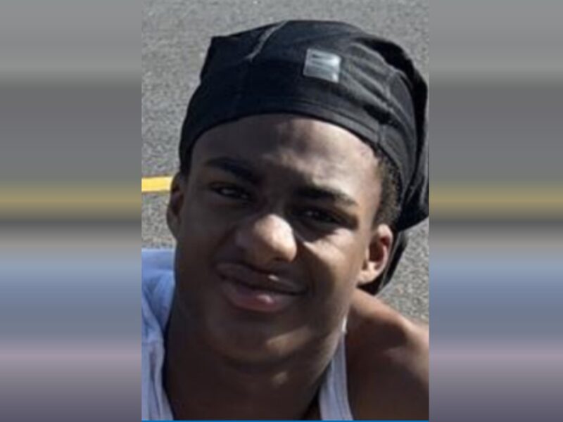 Portrait of a young man wearing a black headwrap and white tank top outdoors.