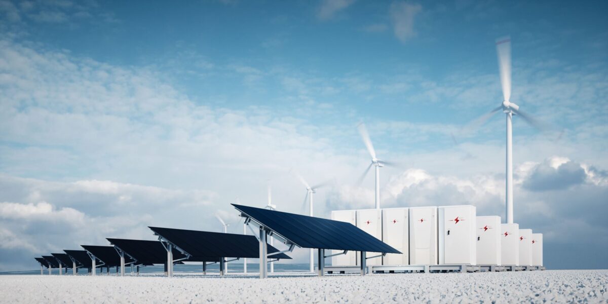 Solar panels and wind turbines beside battery storage units under a blue sky.