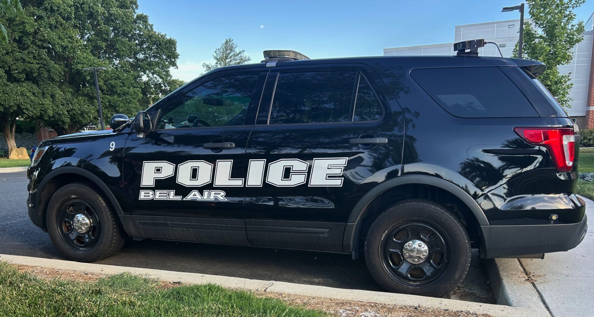 Black Bel Air police SUV parked along a curb on a sunny street.