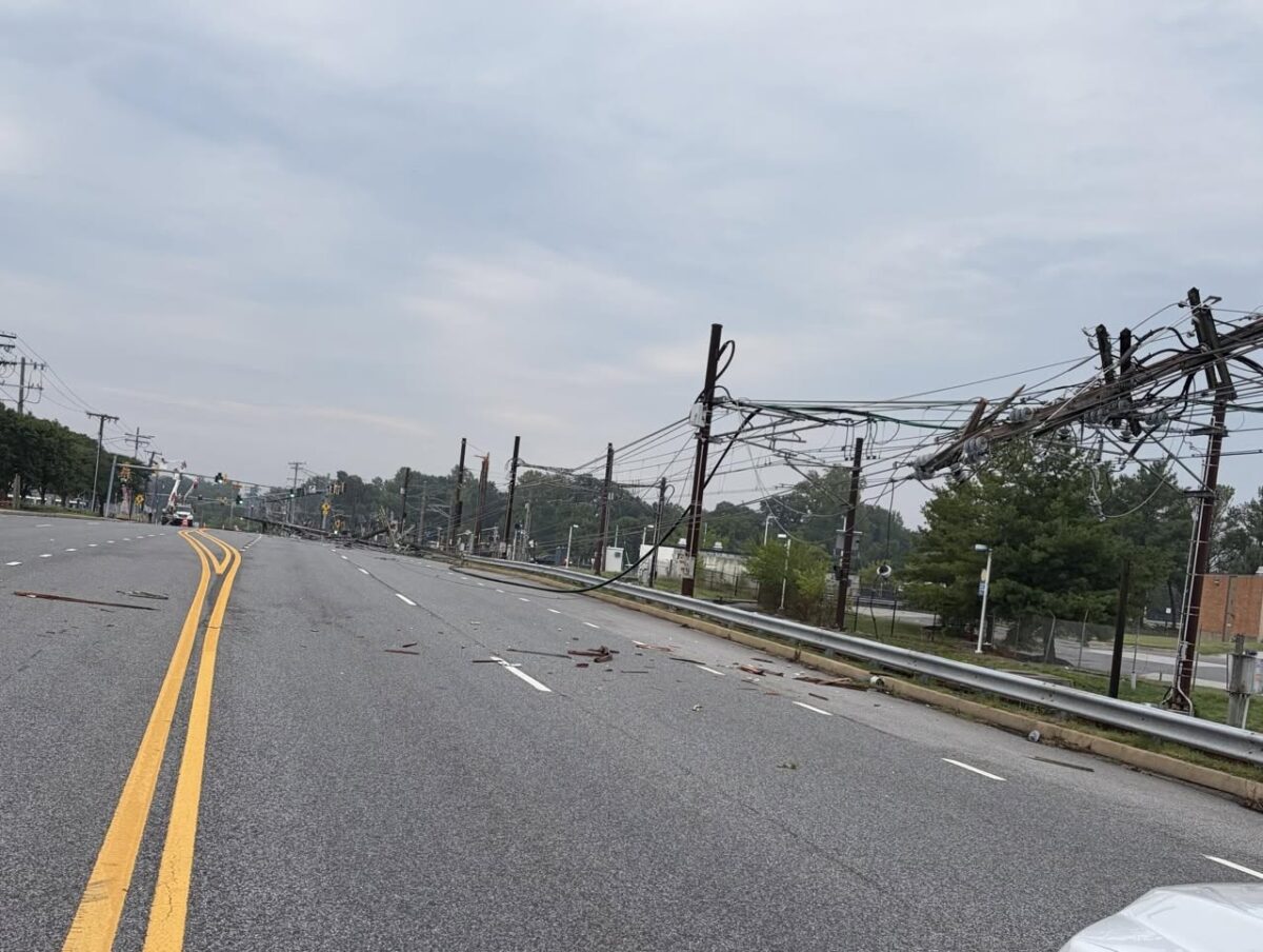 Empty suburban road with downed power lines and debris after a storm.