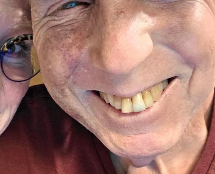 Close-up of a smiling man wearing a cap and maroon shirt.