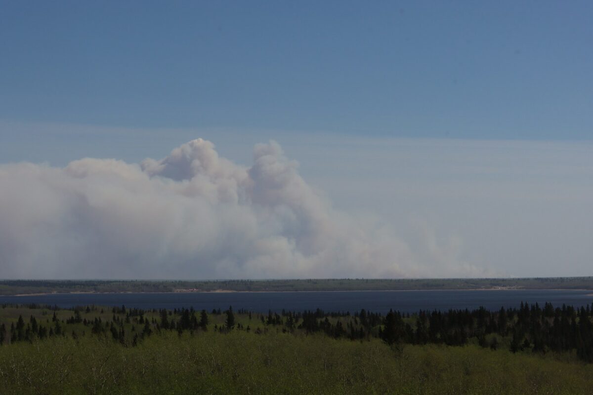 a large plume of smoke rising from a large body of water