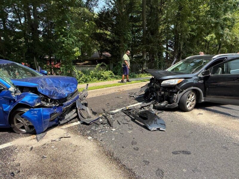 Two damaged cars with a head-on collision scene and debris scattered across the road
