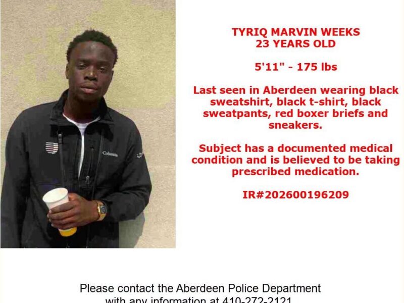 Missing person poster with a man in a black jacket holding a cup beside red text on a white background.