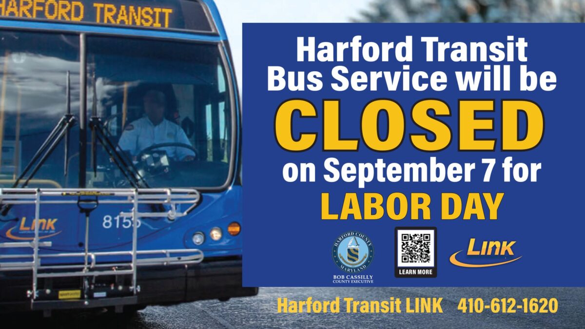 Harford Transit bus beside a sign announcing bus service will be closed on Labor Day.