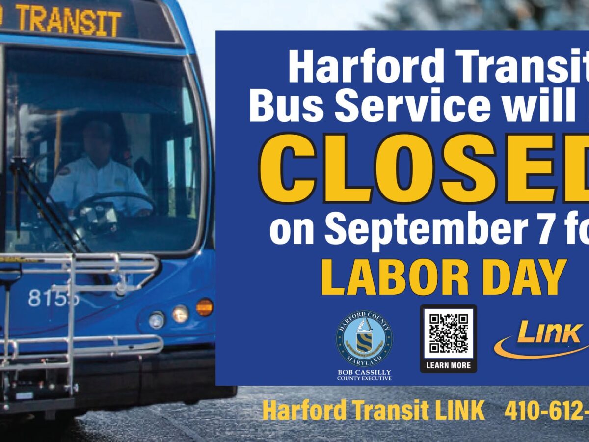 Harford Transit bus beside a sign announcing bus service will be closed on Labor Day.