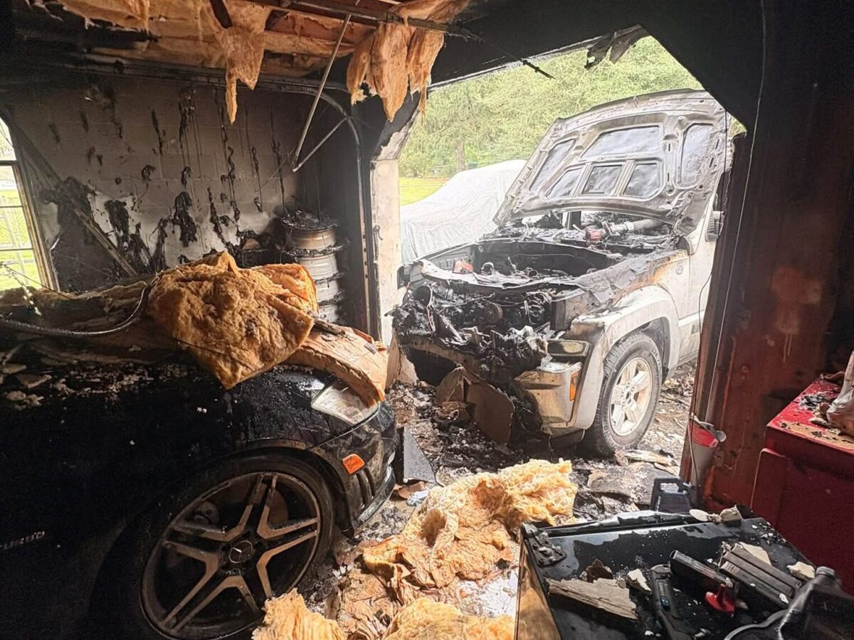Burned vehicles sit in a fire-damaged garage with charred walls and debris.