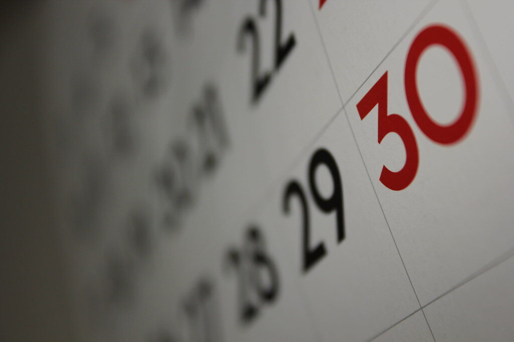 Close-up of a wall calendar showing the dates 29 and 30 in black and red.