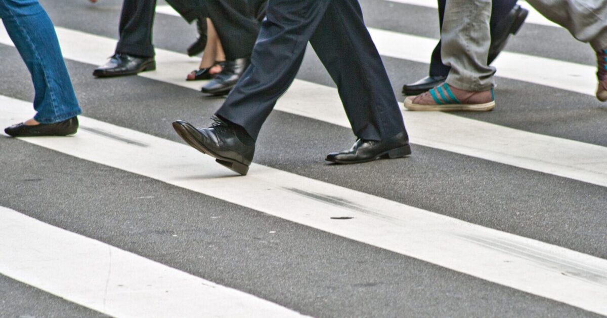 A diverse group of people crossing the street on a zebra pedestrian crossing in a city.