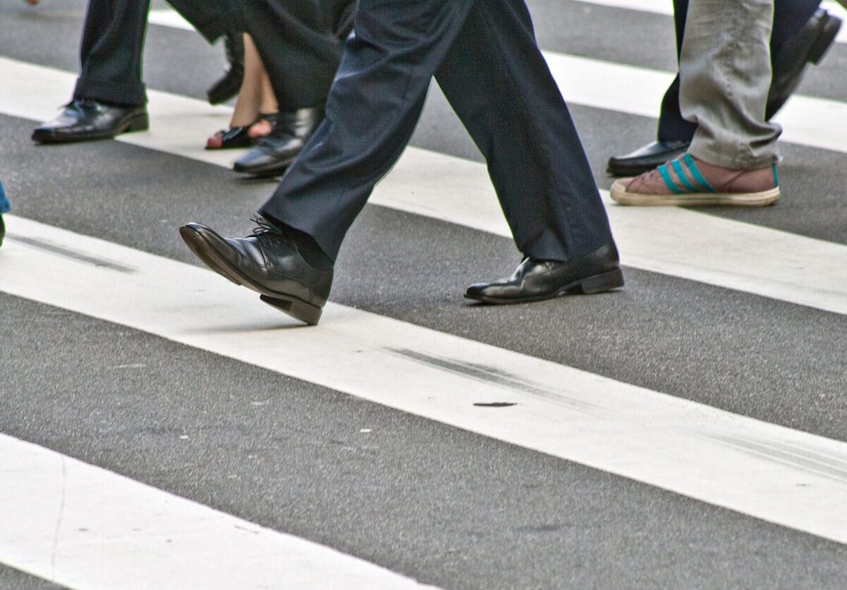 A diverse group of people crossing the street on a zebra pedestrian crossing in a city.