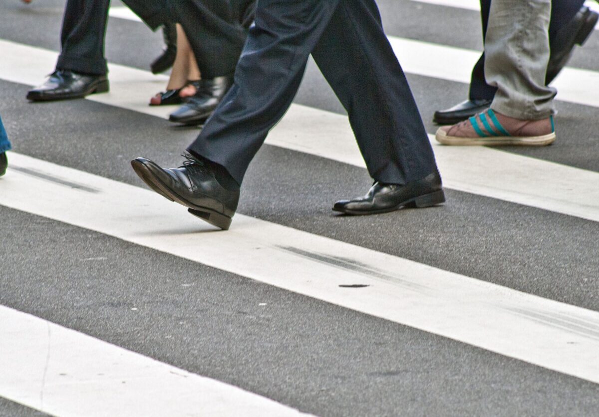 A diverse group of people crossing the street on a zebra pedestrian crossing in a city.