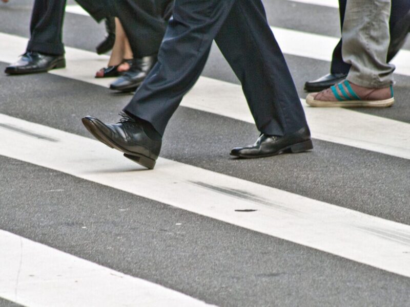 A diverse group of people crossing the street on a zebra pedestrian crossing in a city.